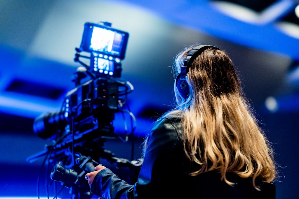 A cameraperson using professional equipment indoors for filming. High-tech setup.