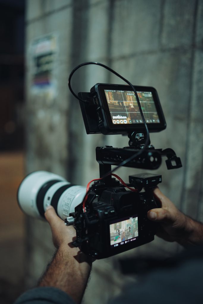 Close-up of a videographer using advanced camera equipment with an external monitor.