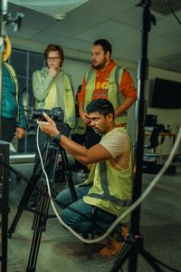 Film crew setting up camera equipment indoors, discussing scene setup and shot composition.
