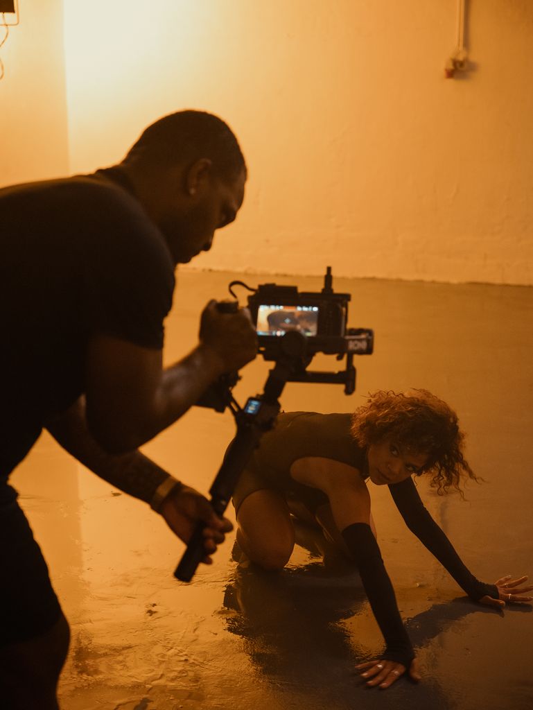 Filmmaker using camera to capture dance performance in an artistic setting.